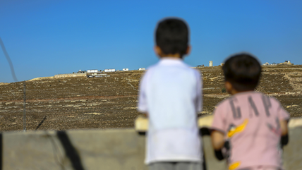 Israeli settlements in the West Bank (Photo: picture alliance / Middle East Images | Mosab Shawer) Two young boys look out from a rooftop at settlements in the West Bank.