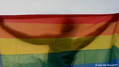 Rainbow flag with silhouette of a man standing behind it