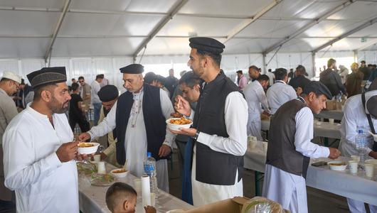 Islamic Peace Conference, August 2025 (Photo: picture alliance/dpa|T. Frey) Muslim men stand around several tables eating food together.