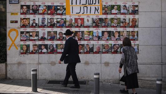 Eine Wand mit Fotos der Hamas-Geiseln und dem Schriftzug: Vergesst uns nicht (Foto: AP Photo/Ohad Zwigenberg) Eine Frau und ein Mann schauen auf die Fotos der Geiseln in Jerusalem